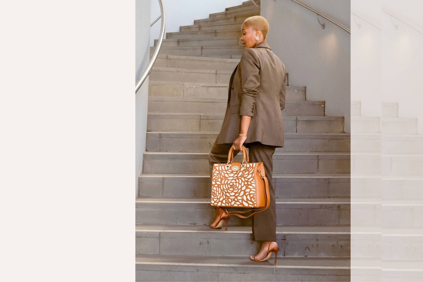 Woman walking up a staircase holding a patterned handbag
