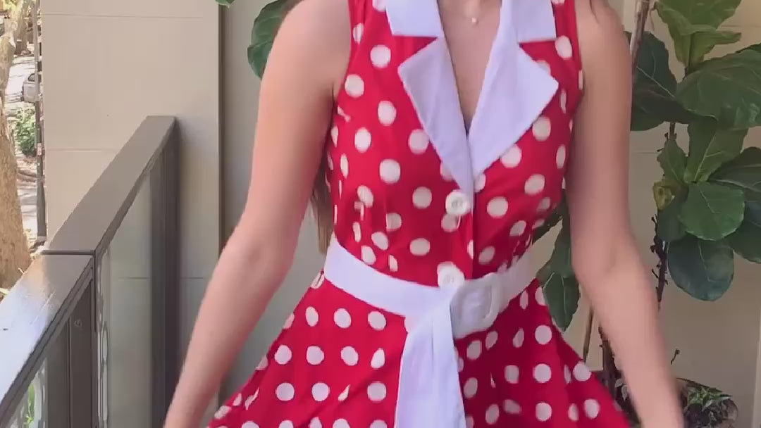 Video of a young women with long , straight light brown hair twirling in a red and white polka dot midi dress.  She is happy ands smiling.  She is on a balcony and you can see a green potted plant and part of a chair with blue cushions in the background.